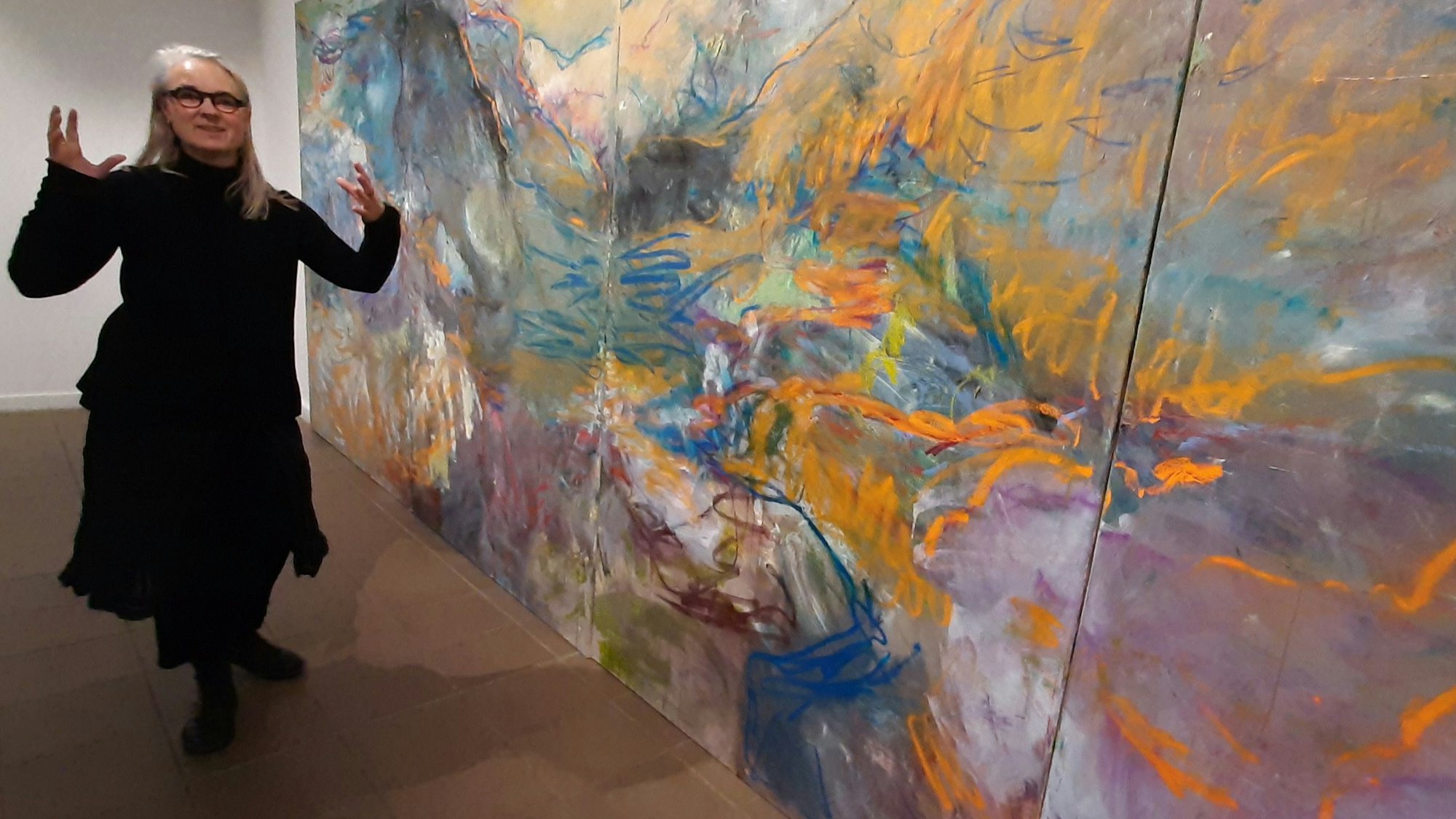 Susanne Wedewer-Pampus steht vor einem großen, bunten Bild.