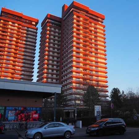 Hochhäuser im Wohnpark Bayenthal mit blauem Himmel und Sonne.