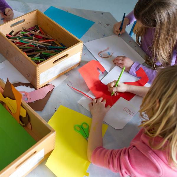 Grundschülerinnen sind in einem Kinderhort mit Bastelarbeiten beschäftigt.