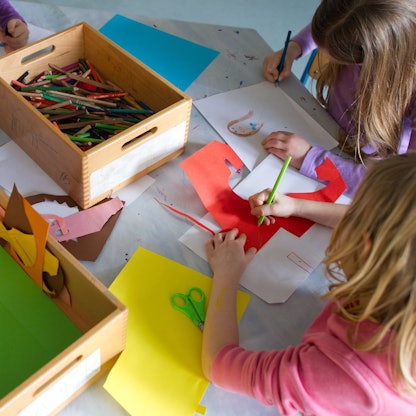 Grundschülerinnen sind in einem Kinderhort mit Bastelarbeiten beschäftigt.