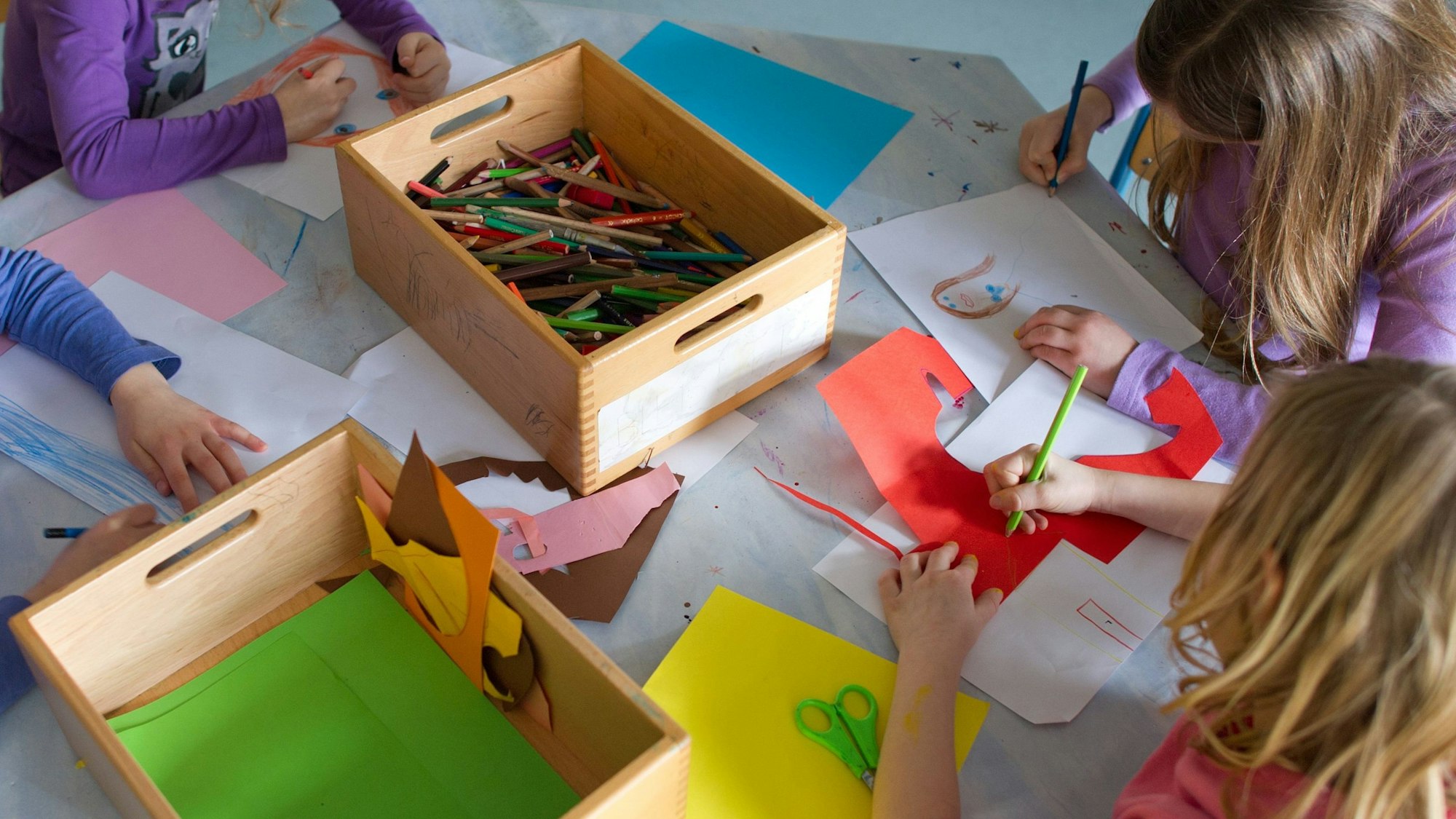 Grundschülerinnen sind in einem Kinderhort mit Bastelarbeiten beschäftigt.