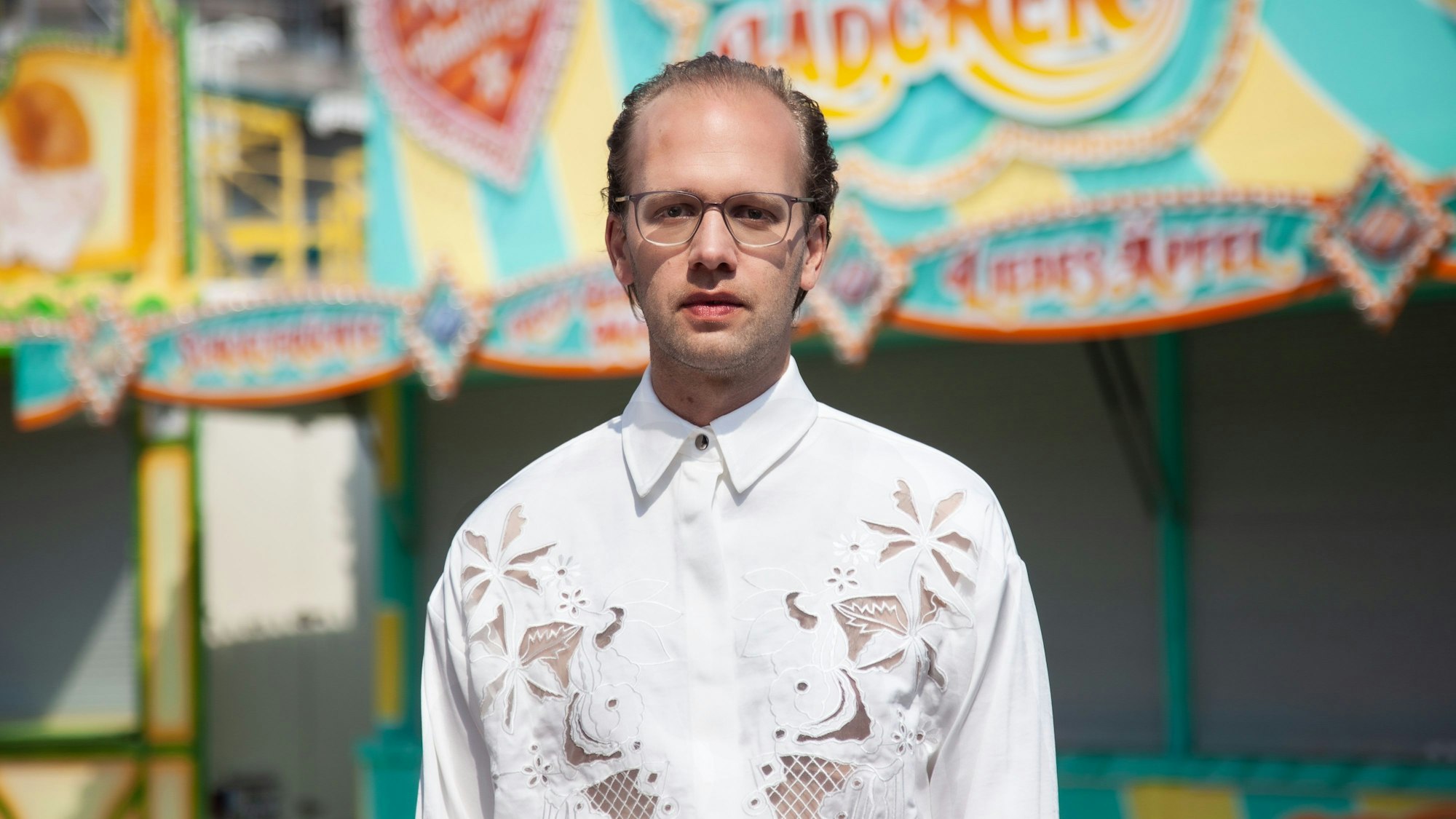 Der Musiker Albrecht Schrader im Porträt vor einer Kirmes.