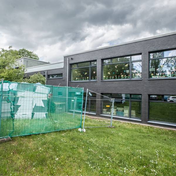 Blick auf einen Bauzaun vor einer Schule