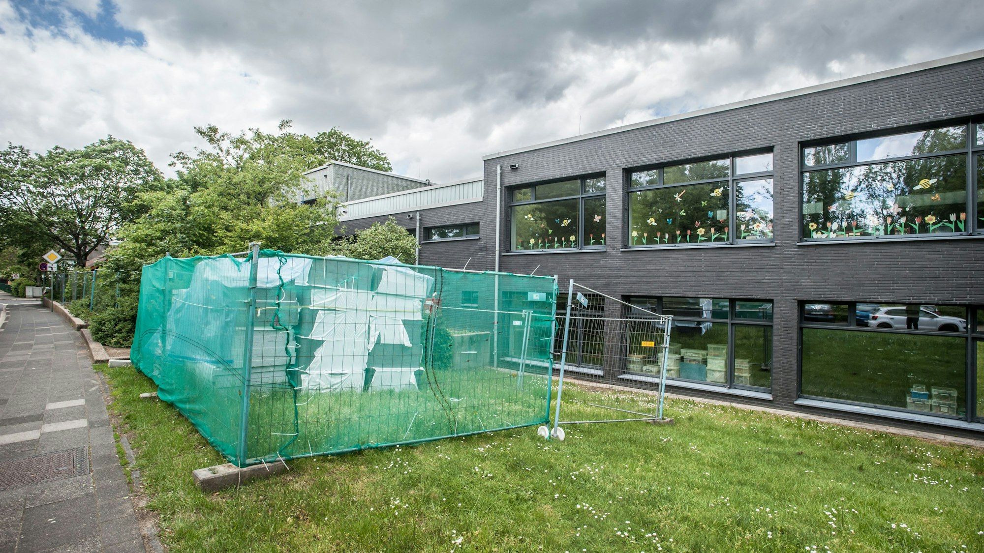 Blick auf einen Bauzaun vor einer Schule
