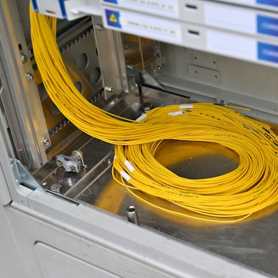 Gelbe Glasfaserkabel liegen in einem Verteilerkasten.