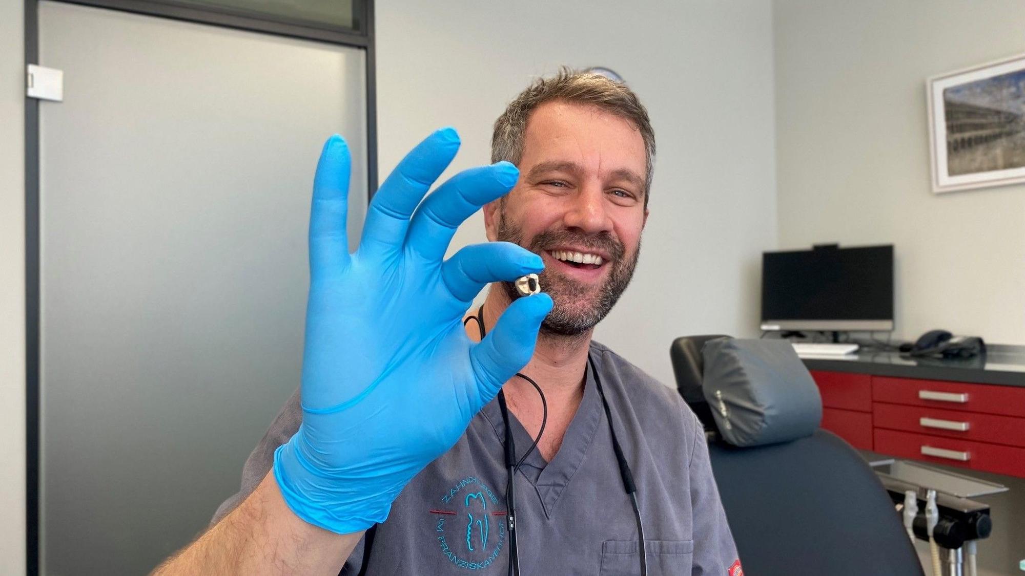 Zahnarzt Benjamin Engelke mit entnommenen Zahngold in der Hand.