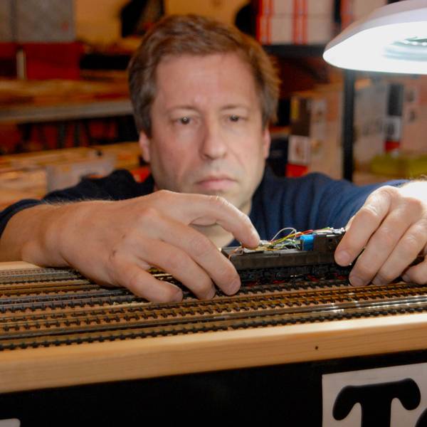 Bahndoktor Dirk Gardemann in seiner Fachwerkstatt mit einer Spielzeugeisenbahn in der Hand.