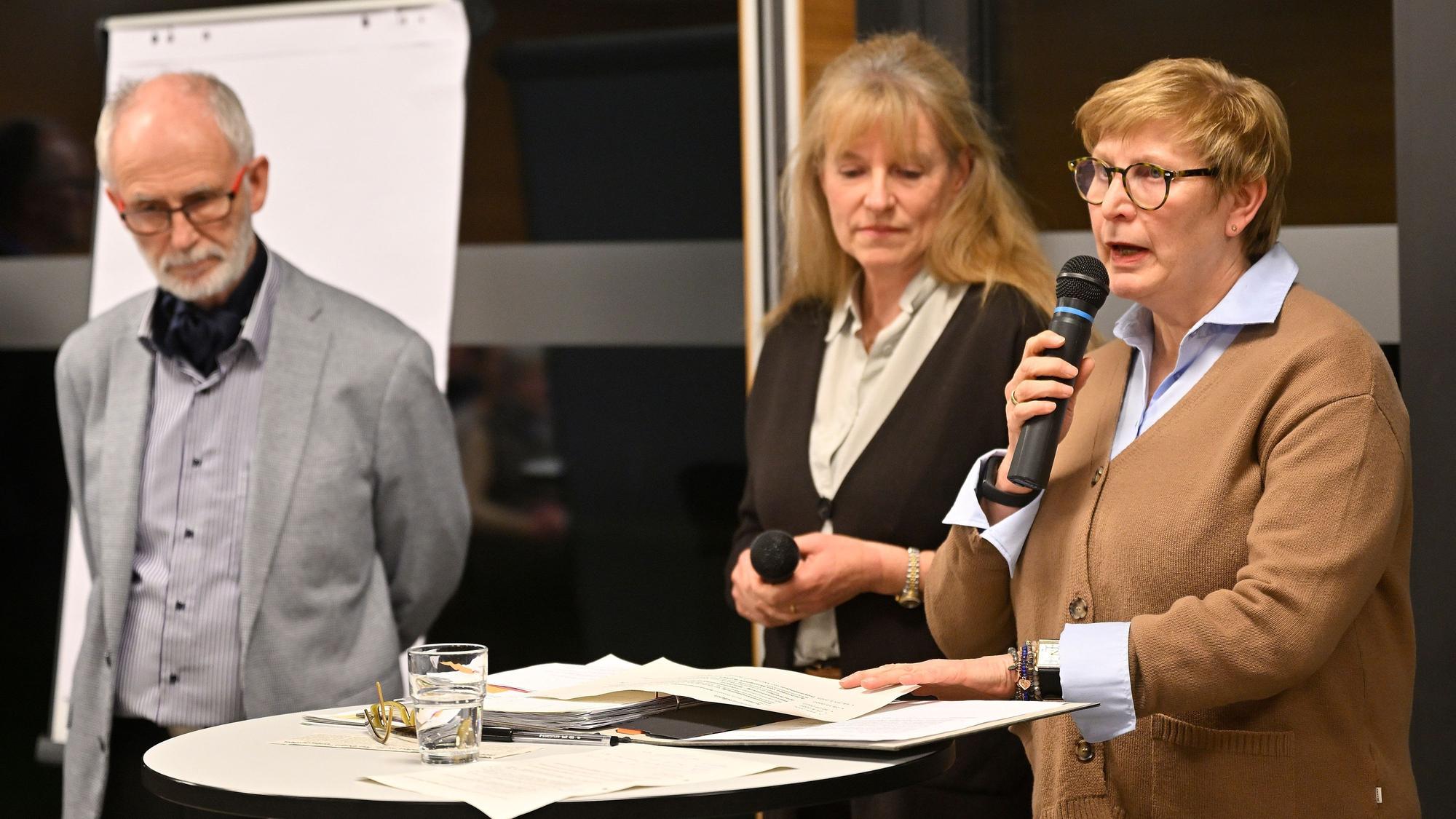 Drei Mitglieder des Kirchenvorstandes und des Orgateams Runder Tisch stehen bei der Pfarrversammlung vorne und richten Worte an die Anwesenden.