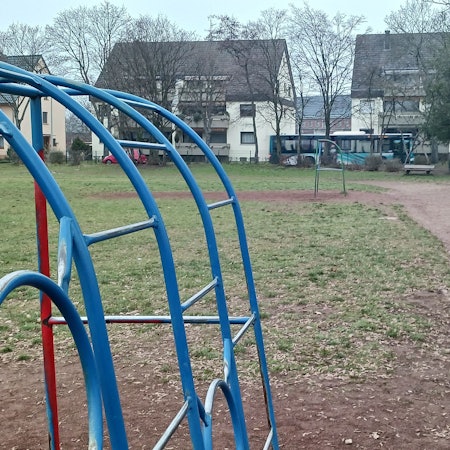 Spielgeräte stehen auf einer verdorrten Wiese.