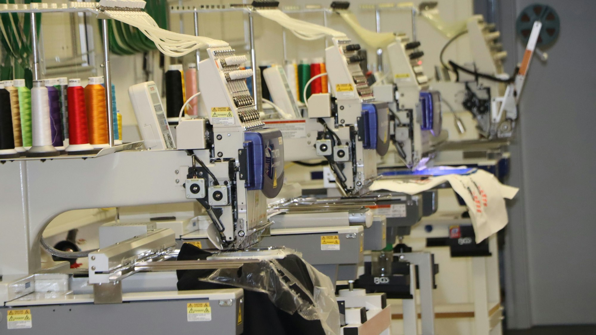 Vier industrielle Stickmaschinen rattern im Atelier in Gleuel.