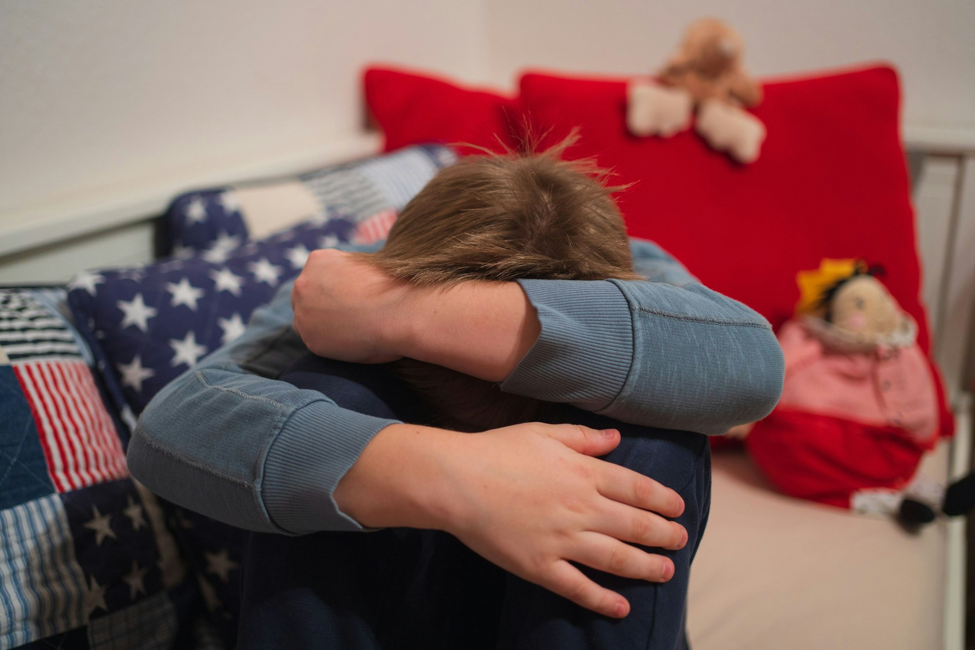 Ein Junge kauert sich auf seinem Bett zusammen.