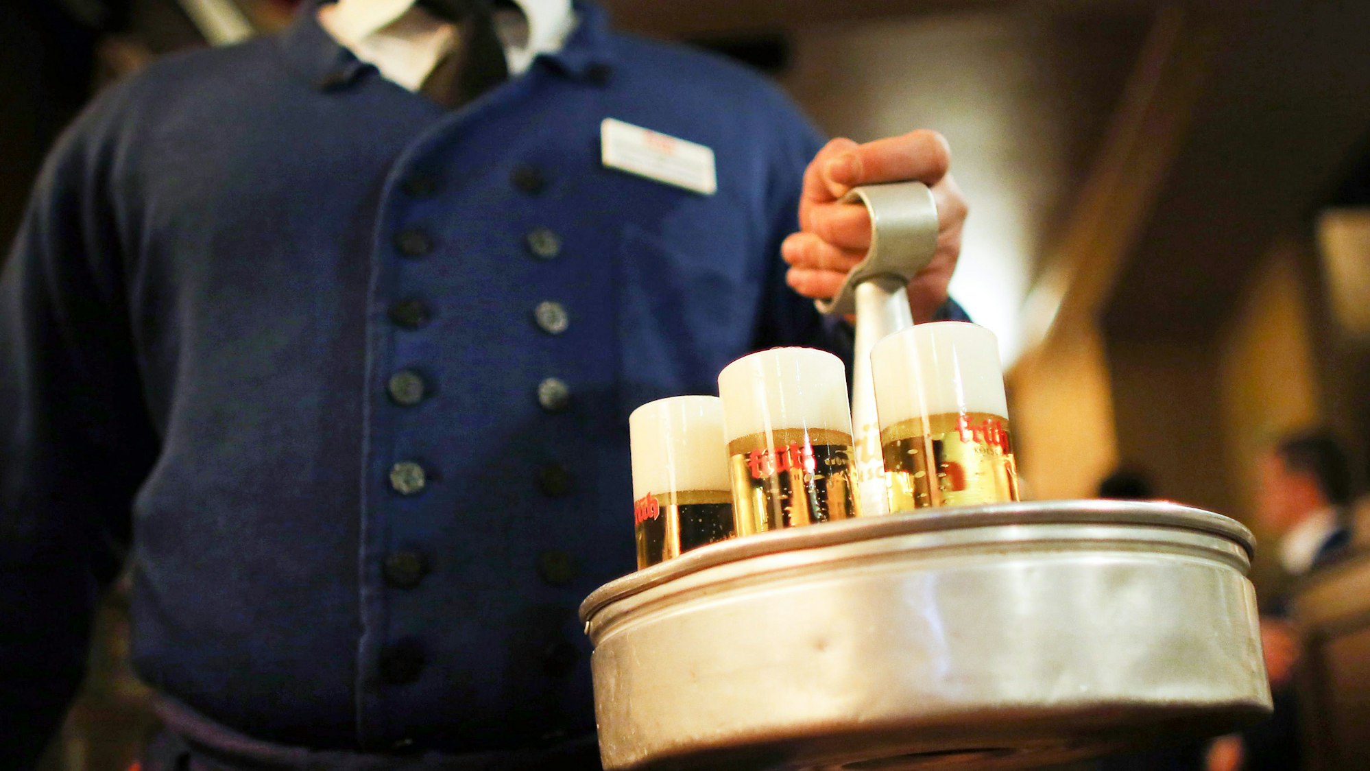 Ein Kellner trägt im Brauhaus Früh am Dom einen Kranz Kölsch.