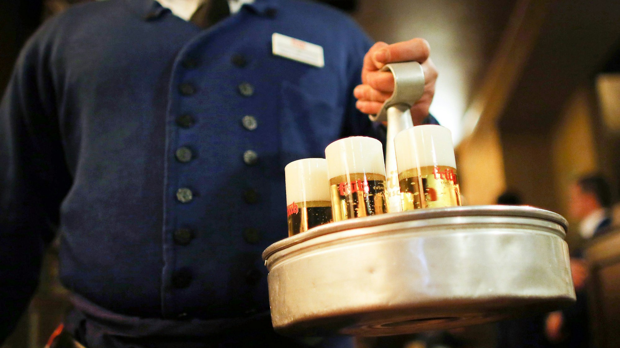 Ein Köbes (Kellner) trägt im Brauhaus Kölsch-Bier.