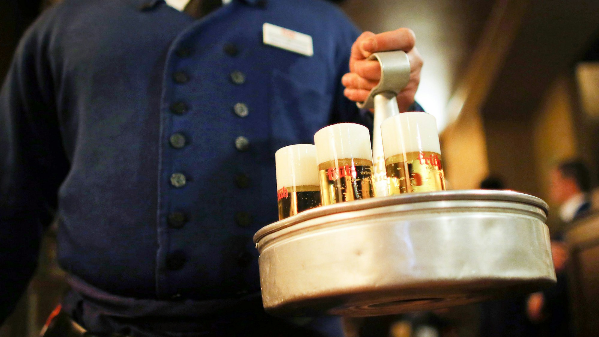 Ein Köbes (Kellner) trägt im Brauhaus Früh am Dom Kölsch-Bier.