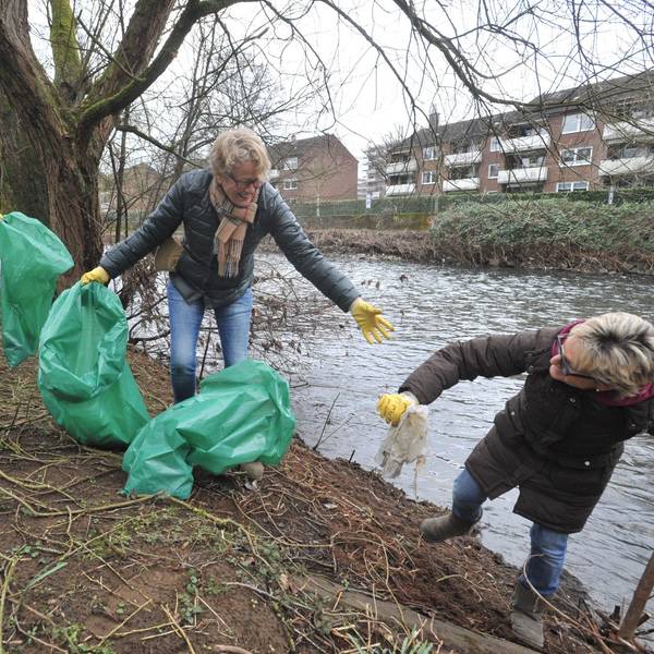 Drei freiwillige Helferinnen mit Müllsäcken am Wupperufer.