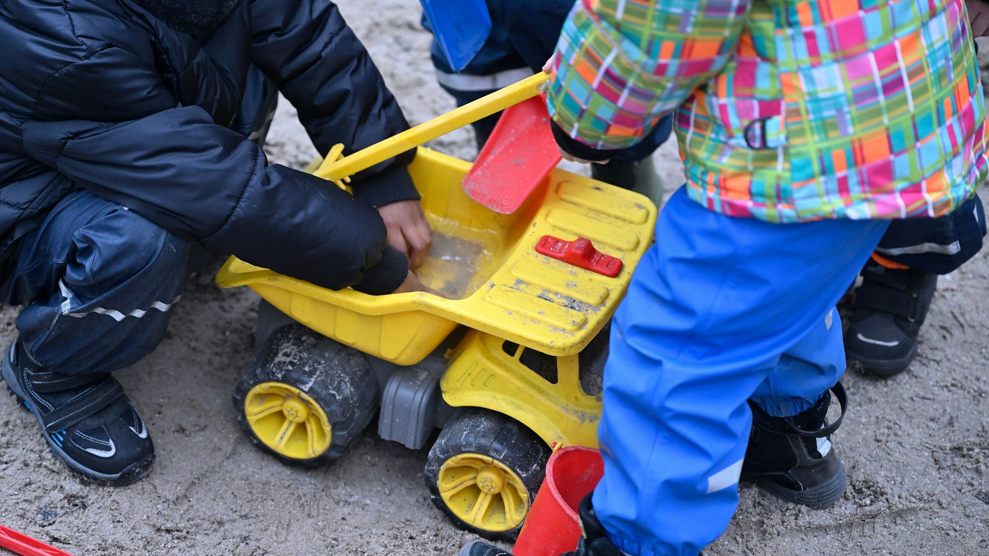 Kinder spielen in einem Sandkasten.