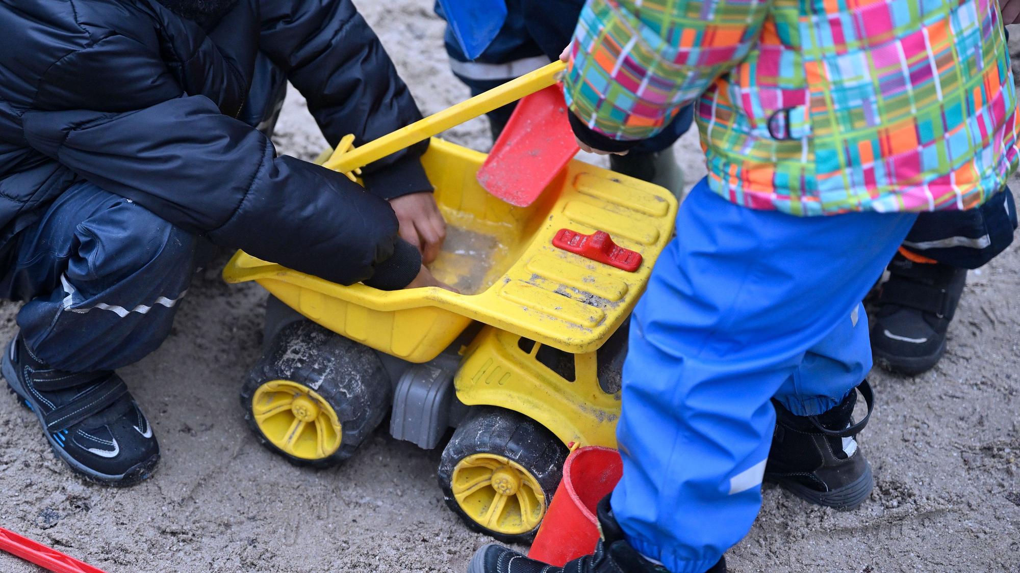 Spielende Kinder im Sandkasten eines Kindergartens.