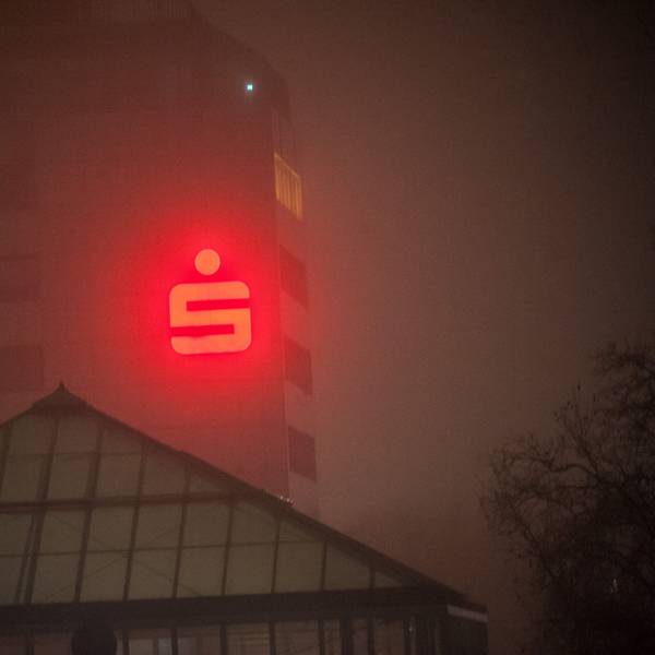 Das rote Logo der Sparkasse Leverkusen an der Fassade des Sparkassen-Gebäudes in Leverkusen-Wiesdorf durchdringt den Nebel.
