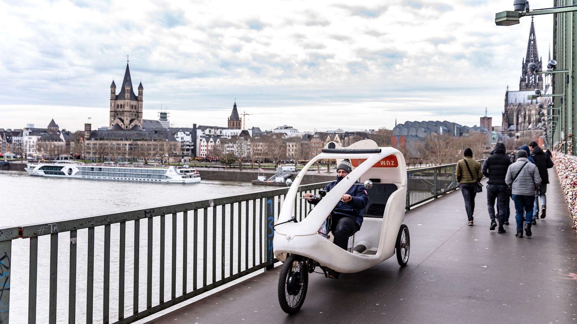 weiße Rikscha auf einer Brücke über dem Rhein