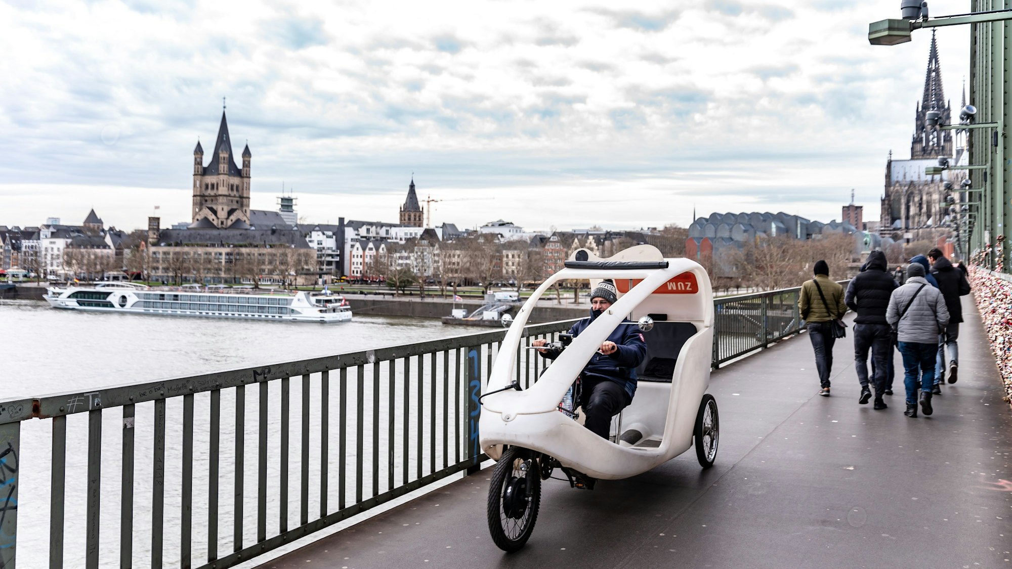 weiße Rikscha auf einer Brücke über dem Rhein