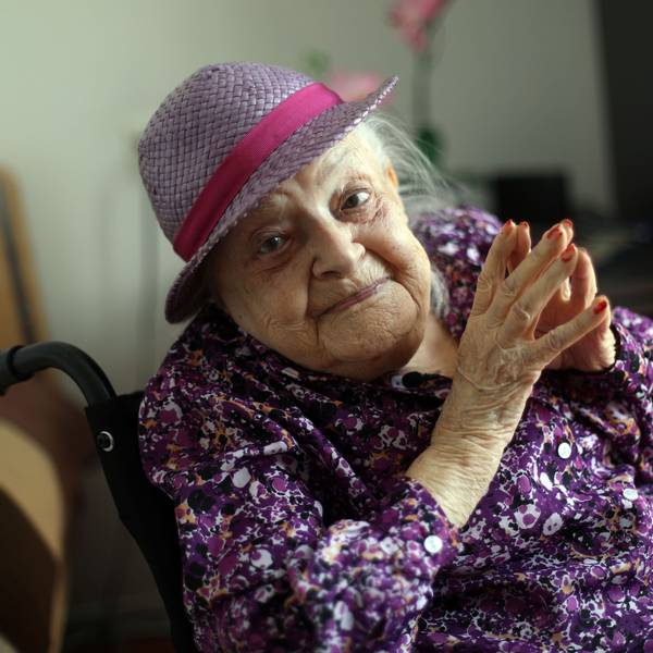 Faye Cukier trägt an ihrem 100. Geburtstag ein lila Hütchen und ein lila Hemd. Sie schaut lächelnd in die Kamera.