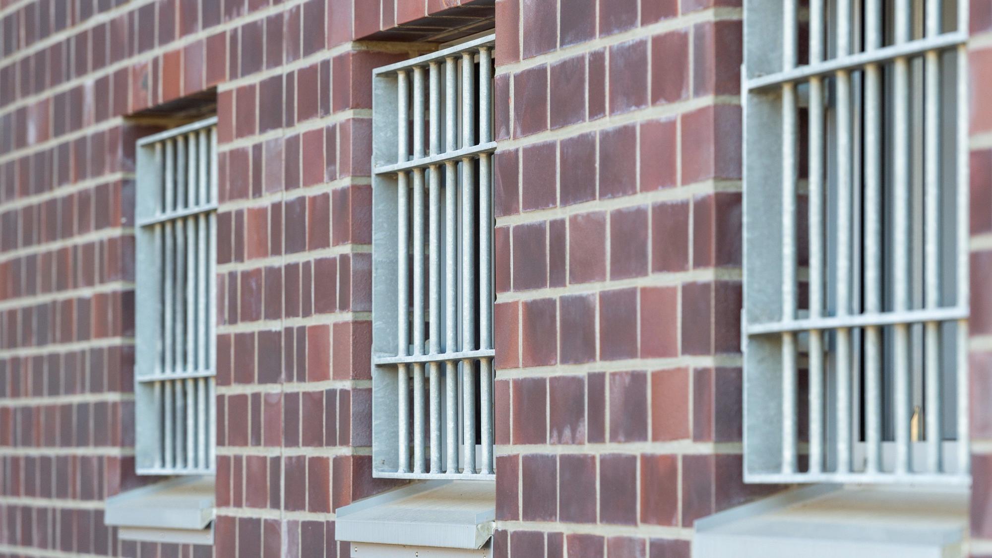 Die Fenster einer Justizvollzugsanstalt sind vergittert.