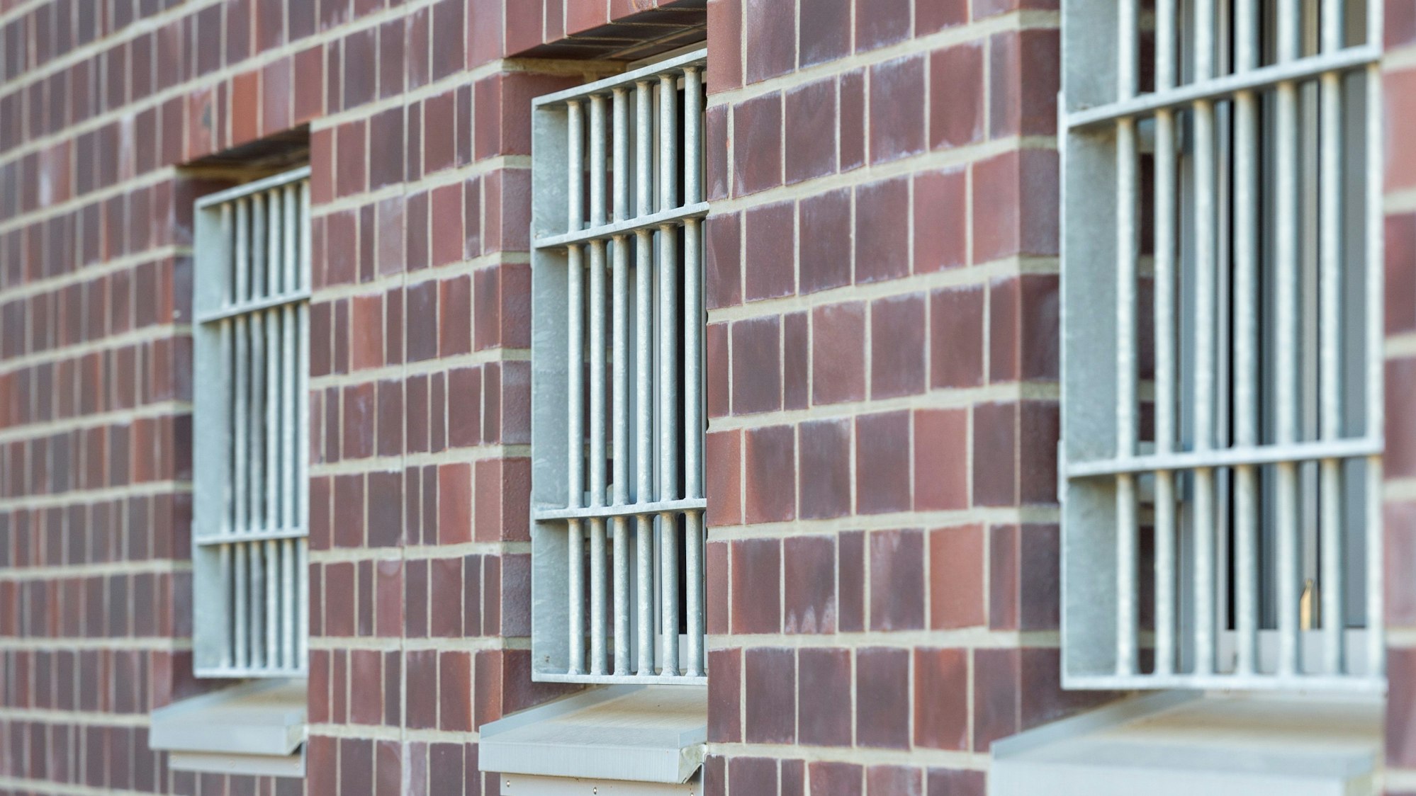 Die Fenster einer Justizvollzugsanstalt sind vergittert.