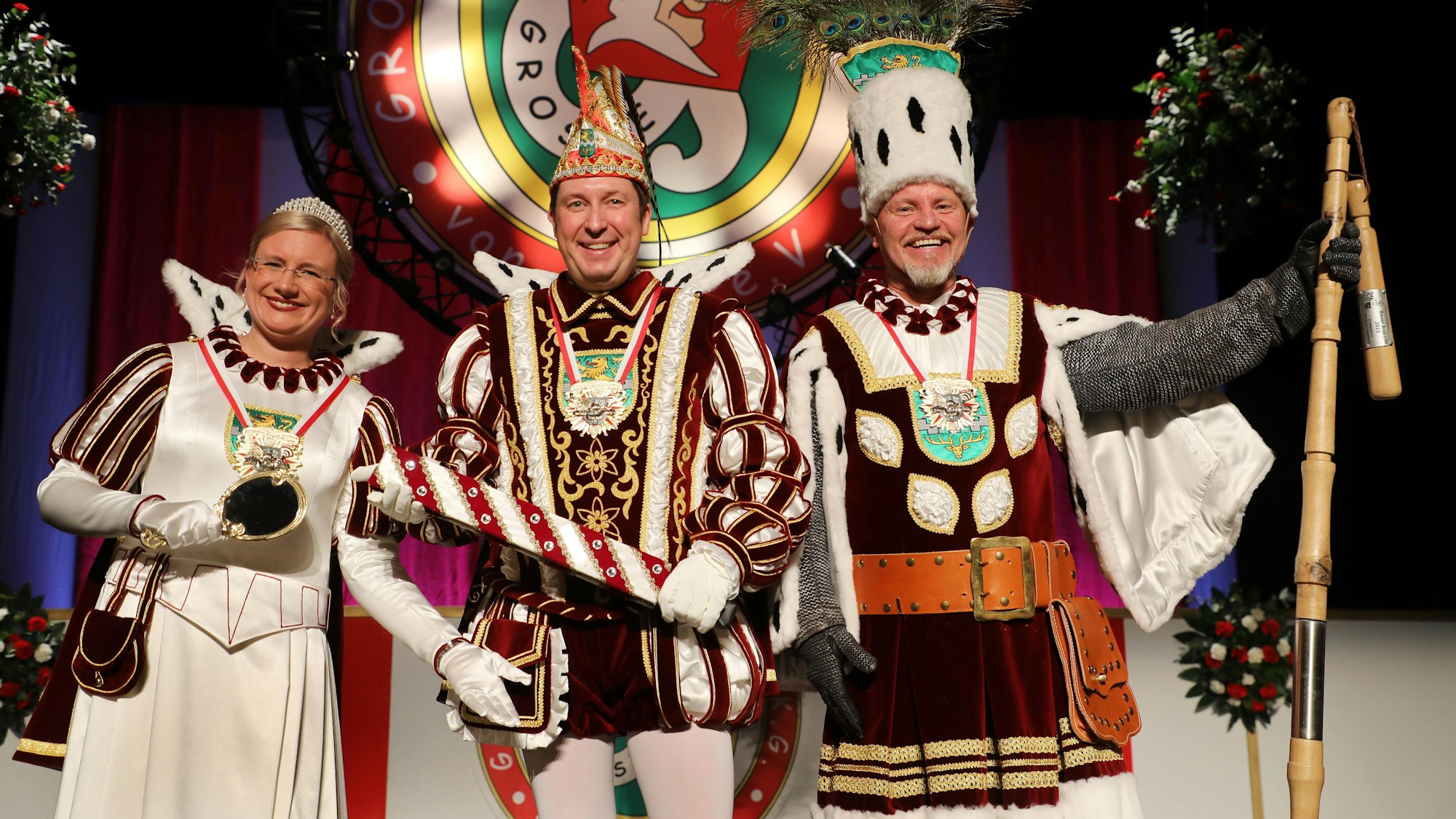Das Dreigestirn steht in Ornaten auf der Bühne.