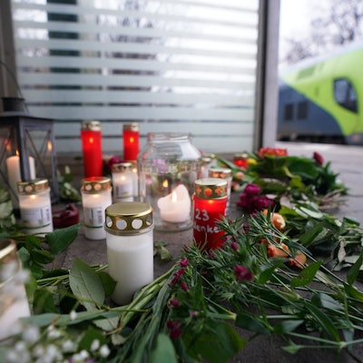 Blumen und Kerzen liegen an einer Bahnhaltestelle.