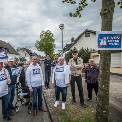 Rund 20 Menschen stehen auf der Straße und protestieren gegen den Autobahnausbau.