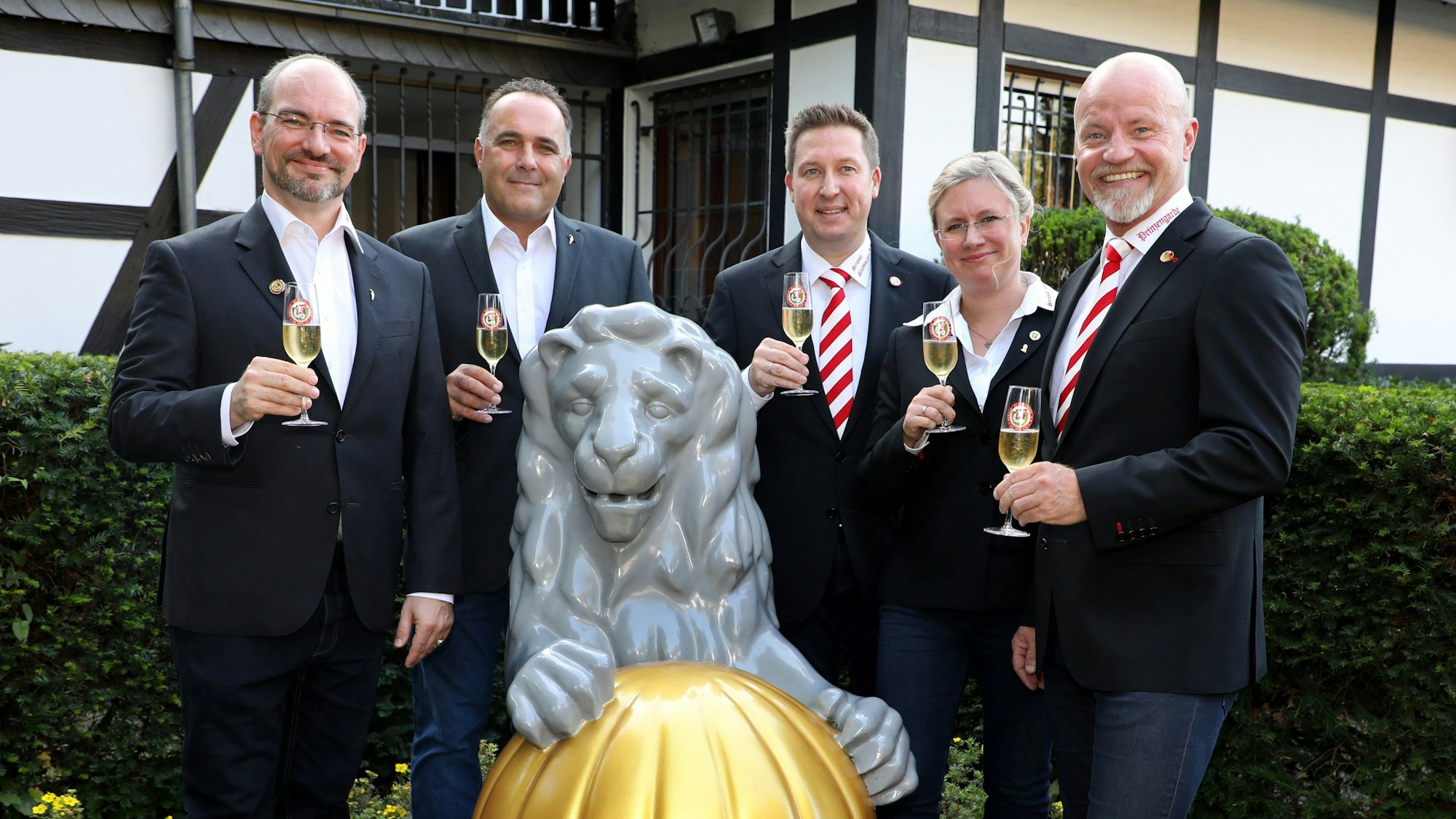 Das Dreigestirn mit KG-Präsident und Prinzenführer vorm Alten Lindenhof mit Sektgläsern in der Hand.