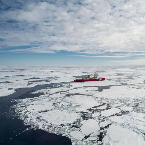 Das rote Schiff der US Küstenwache bricht durch das Packeis der Antatrktis, der Himmel ist bewölkt.