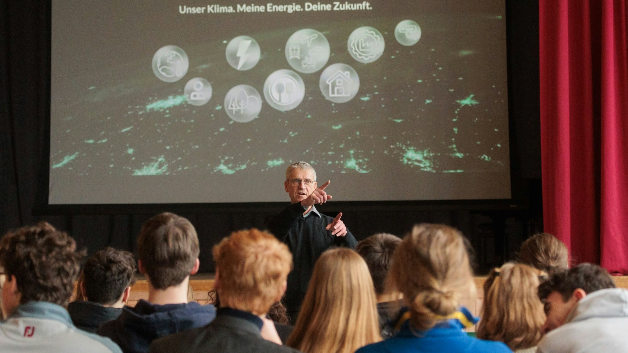 Der Biologe Stefan Simonis steht vor einer Leinwand. Vor ihm sitzen mehrere Schüler und Schülerinnen.