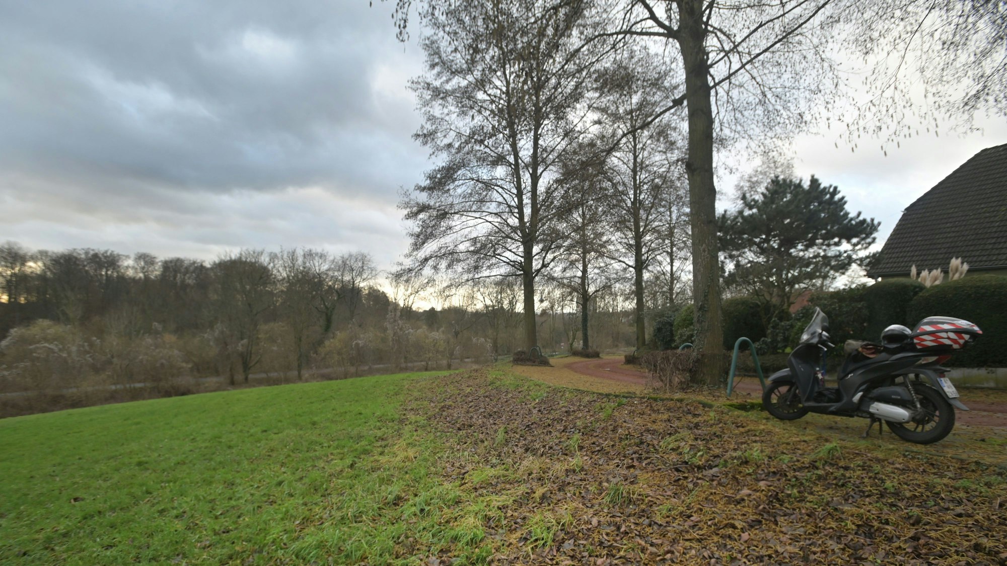Nach links abfallende Wiese, rechts parkt ein Motorroller