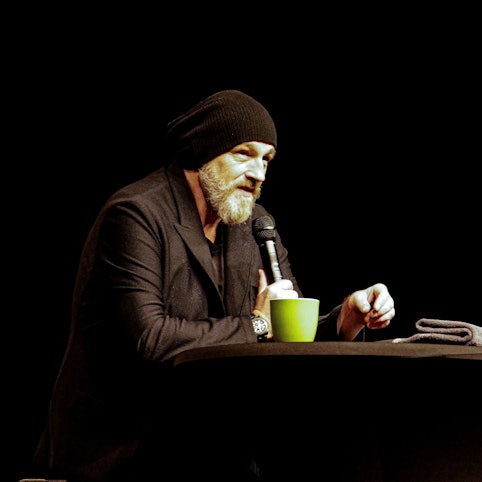 Torsten Sträter trägt einen schwarzen Anzug und eine schwarze Mütze.