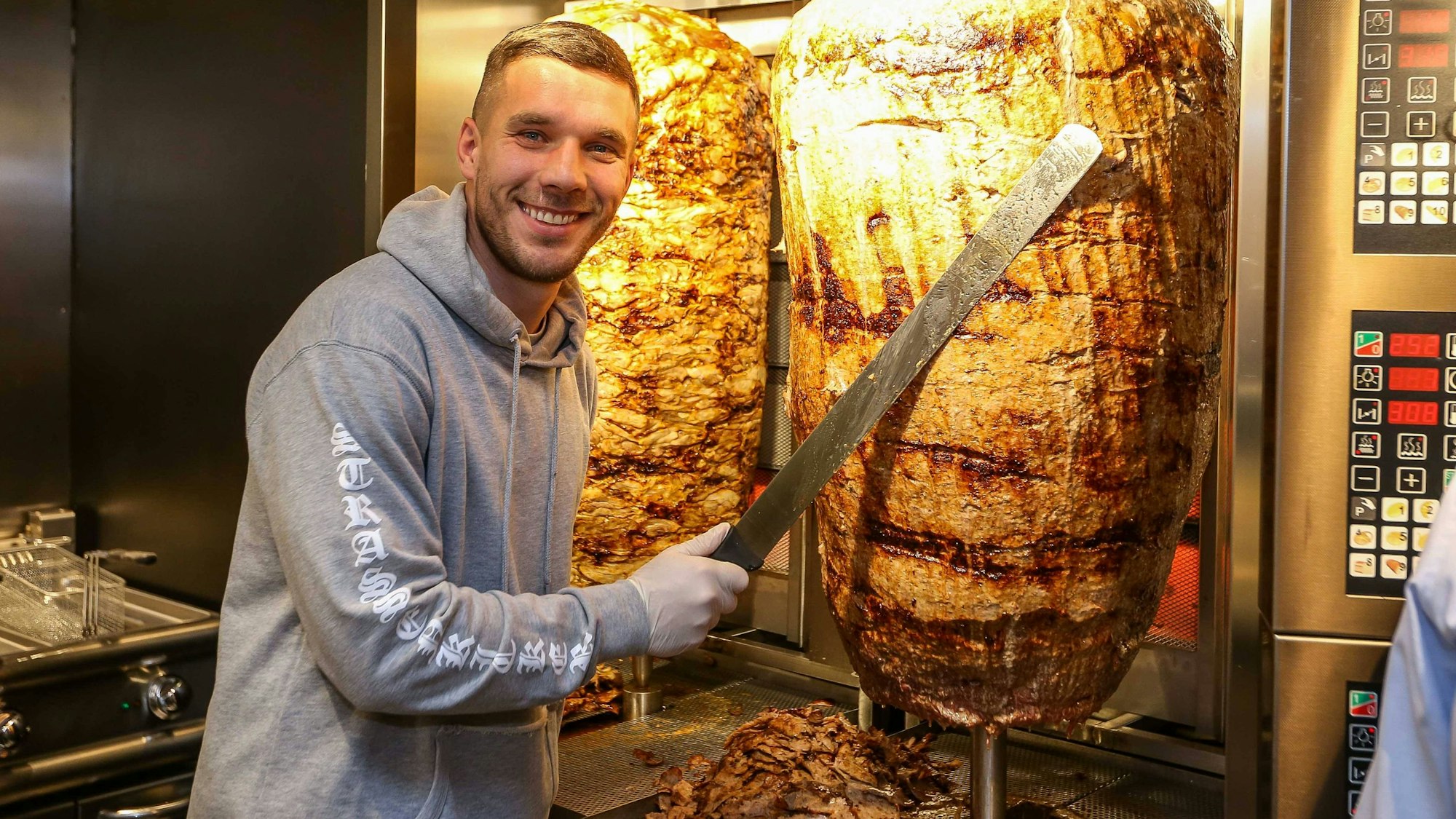 Podolski im Laden am Chlodwigplatz am Dönerspieß mit Messer