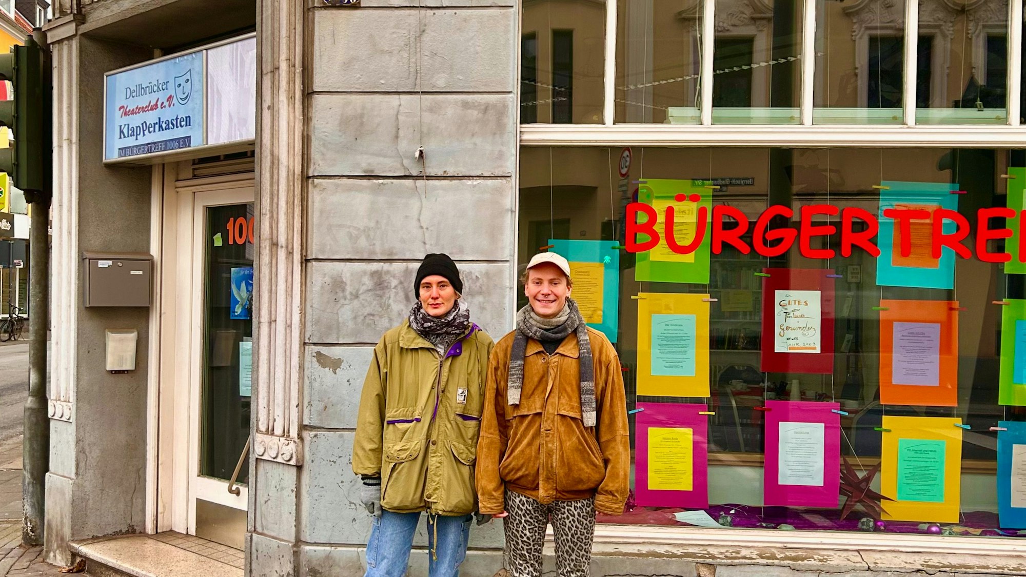 Vor einem Haus stehen eine Frau und ein Mann. In einem Fenster ist die Schriftzeile Bürgertreff zu sehen.