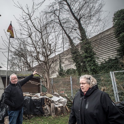Gisela Kronenberg im Garten von Rolf Luxem (Ratherkämp 8): zwei meter höher als die alte Lärmschutzmauer wird die neue Mauer, höher als die Fahnenstange sie stünde mitten im garten (etwa beim Trampolin). Foto: Ralf Krieger