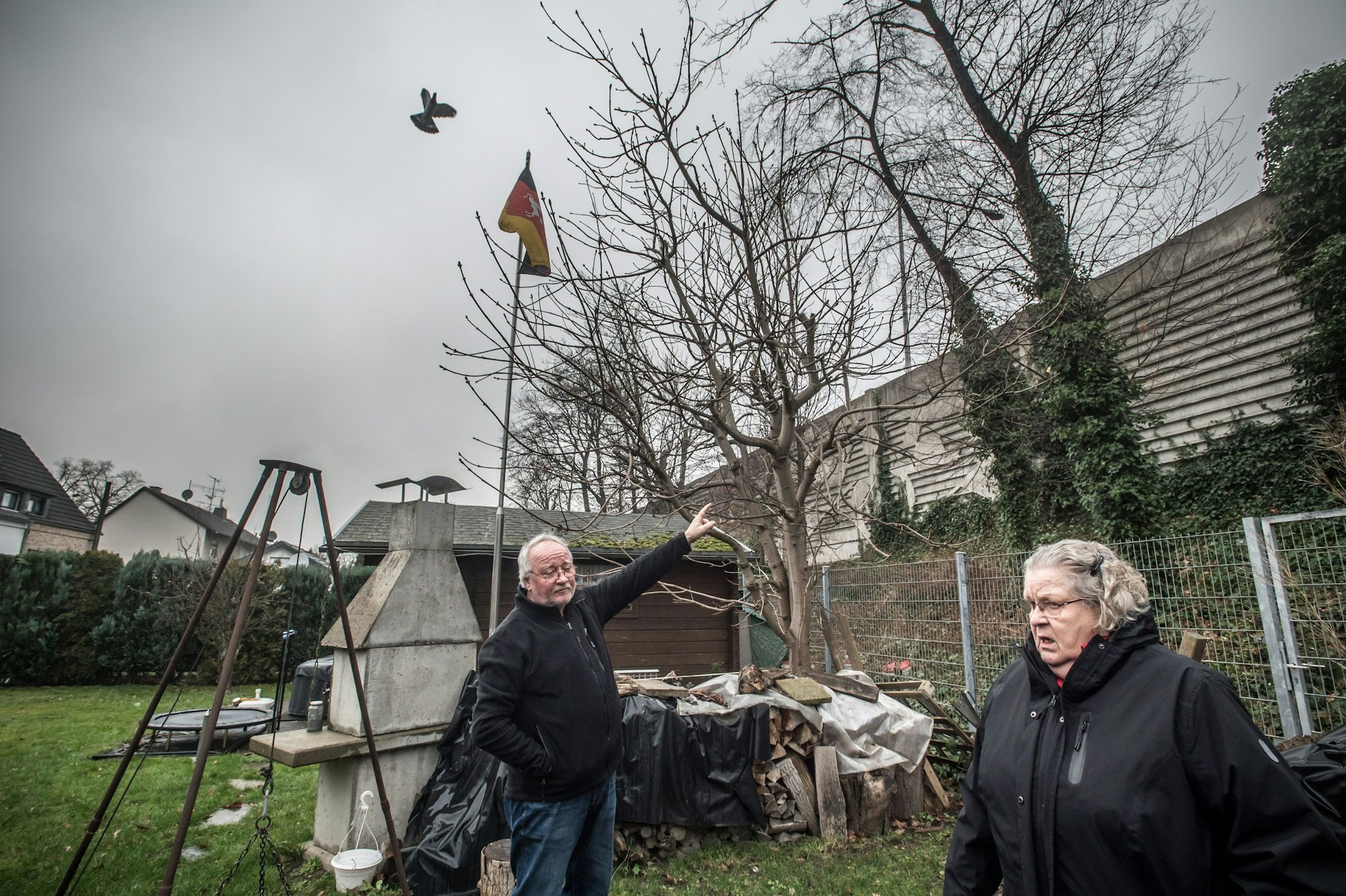 Gisela Kronenberg im Garten von Rolf Luxem (Ratherkämp 8): zwei meter höher als die alte Lärmschutzmauer wird die neue Mauer, höher als die Fahnenstange sie stünde mitten im garten (etwa beim Trampolin). Foto: Ralf Krieger
