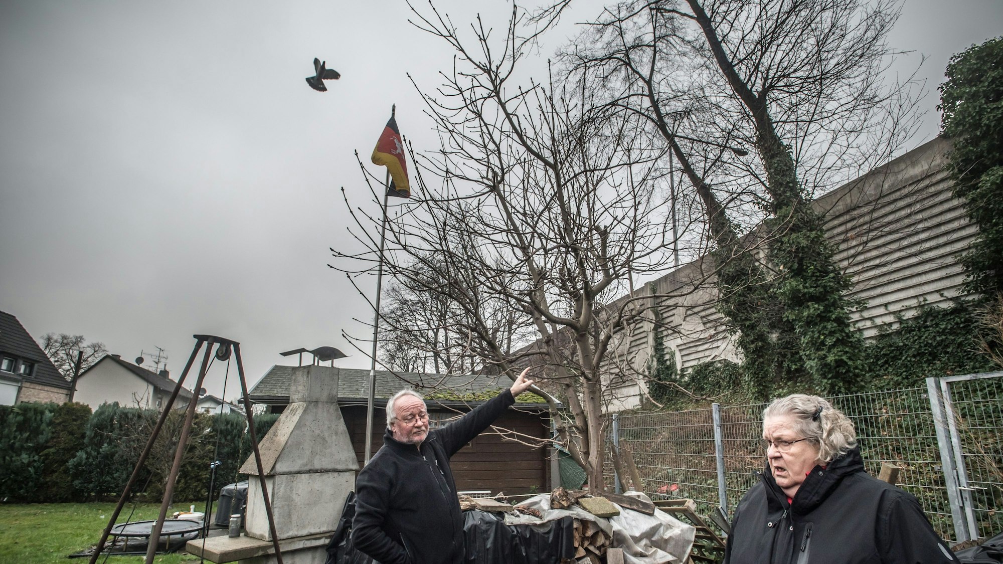 Gisela Kronenberg im Garten von Rolf Luxem (Ratherkämp 8): zwei meter höher als die alte Lärmschutzmauer wird die neue Mauer, höher als die Fahnenstange sie stünde mitten im garten (etwa beim Trampolin). Foto: Ralf Krieger