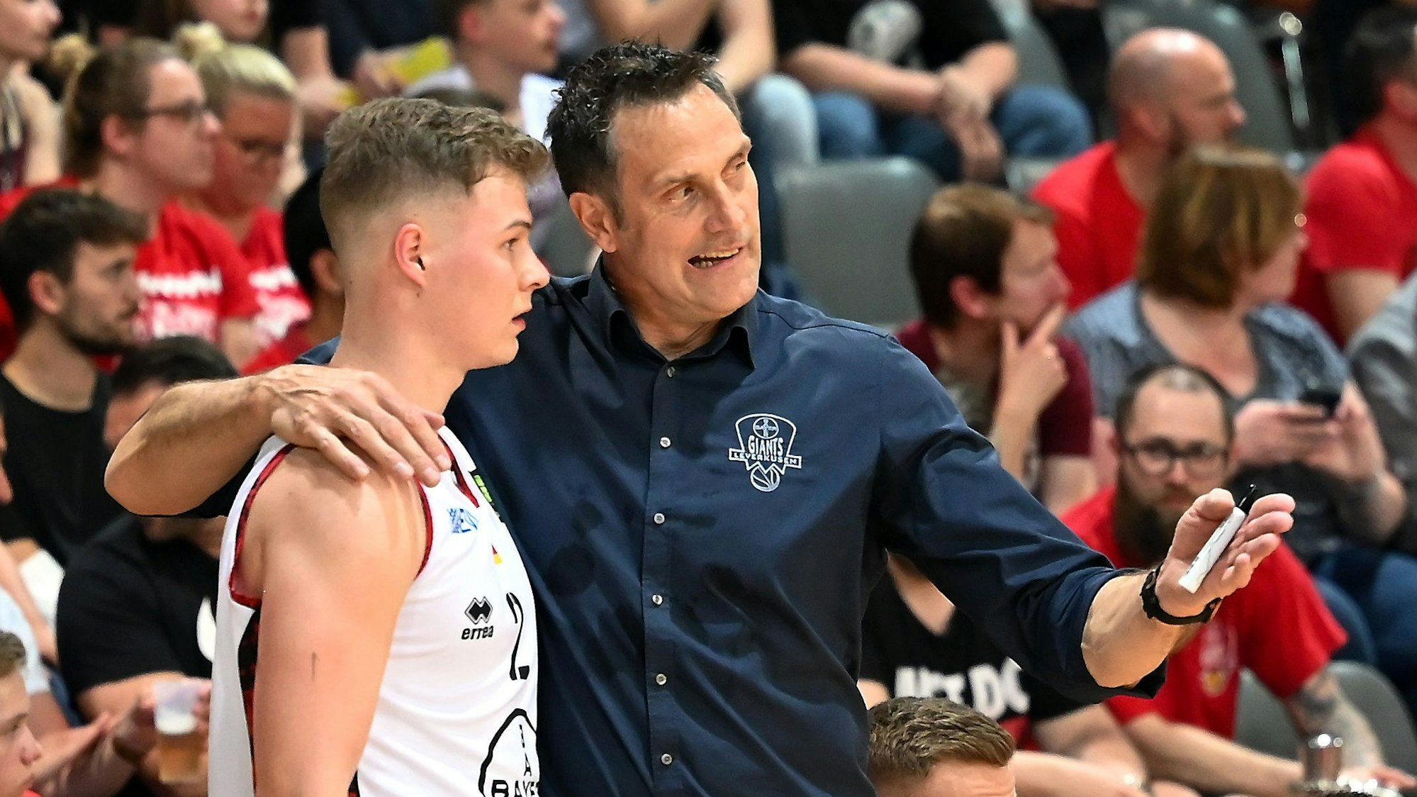 Ein Basketballtrainer legt den Arm um seinen Spieler und erklärt ihm etwas.