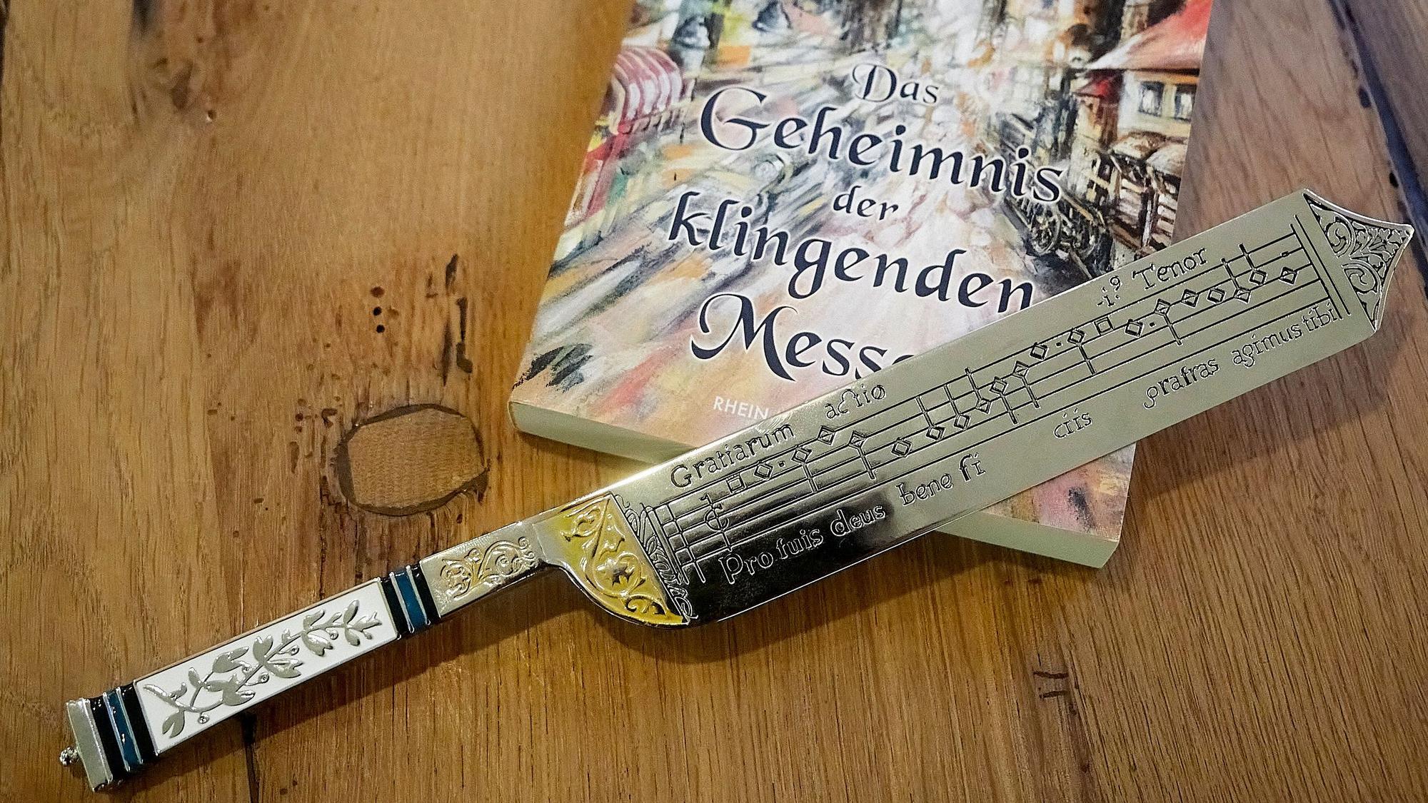 Ein kunstvoll gearbeitet Messer mit eingravierten Musik-Noten liegt auf einem Buch.