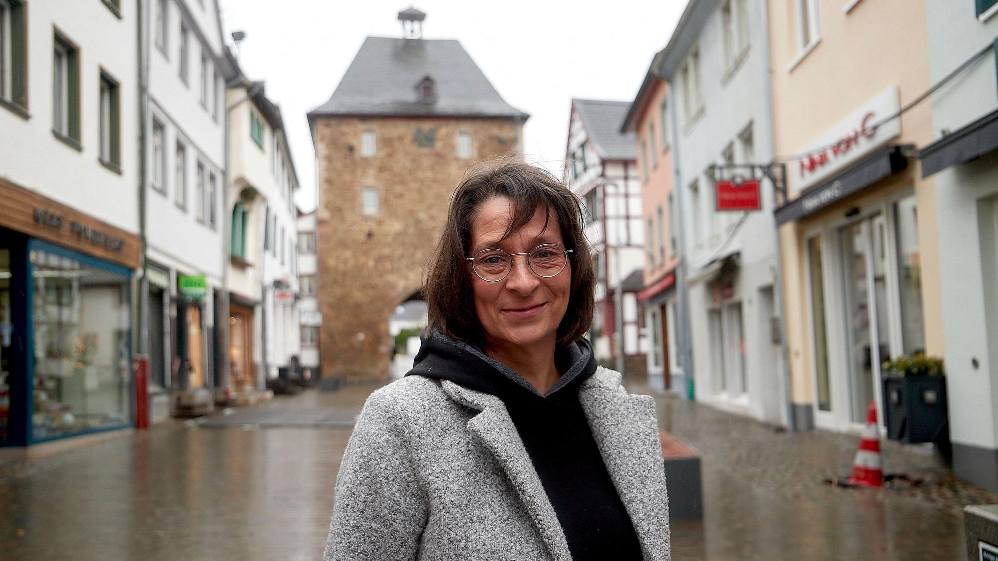 Eine Frau steht auf einer Straße in Bad Münstereifel, im Hintergrund ist das Orchheimer Tor zu sehen.