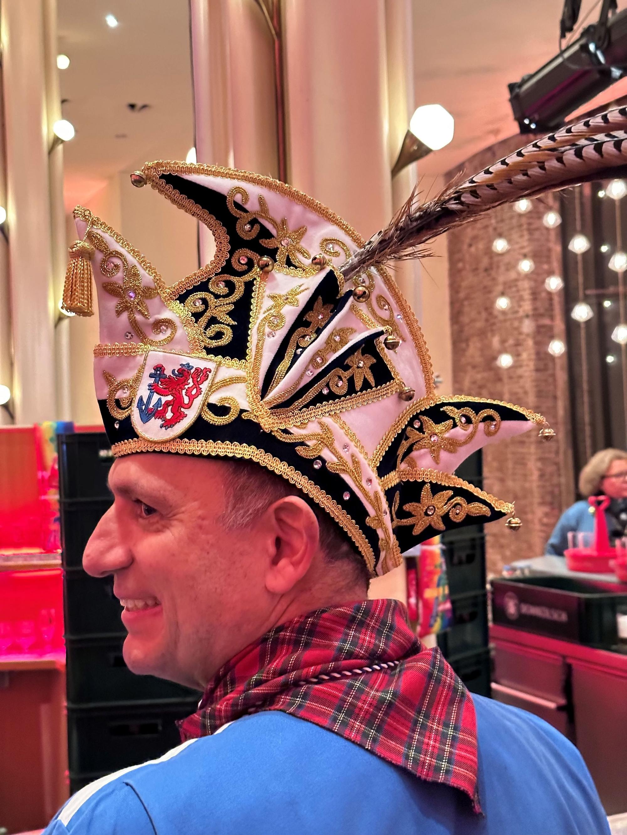 Ein Mann mit schwarz-weißer, goldbesetzter Narrenkappe.