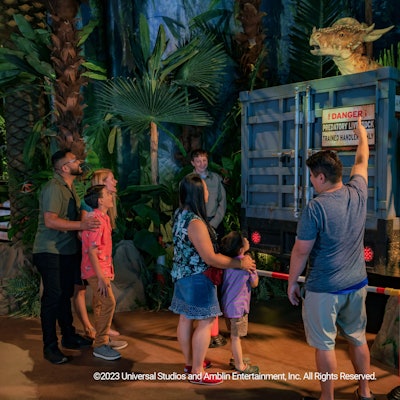 Mehrere Besucher der Jurassic-World-Ausstellung stehen vor einem Modell-Dinosuarier.