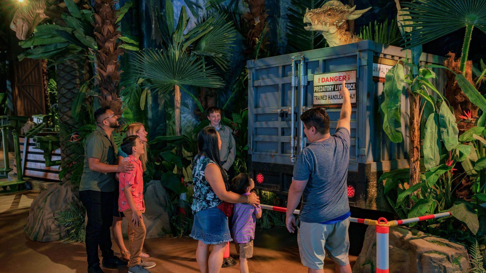 Mehrere Besucher der Jurassic-World-Ausstellung stehen vor einem Modell-Dinosuarier.