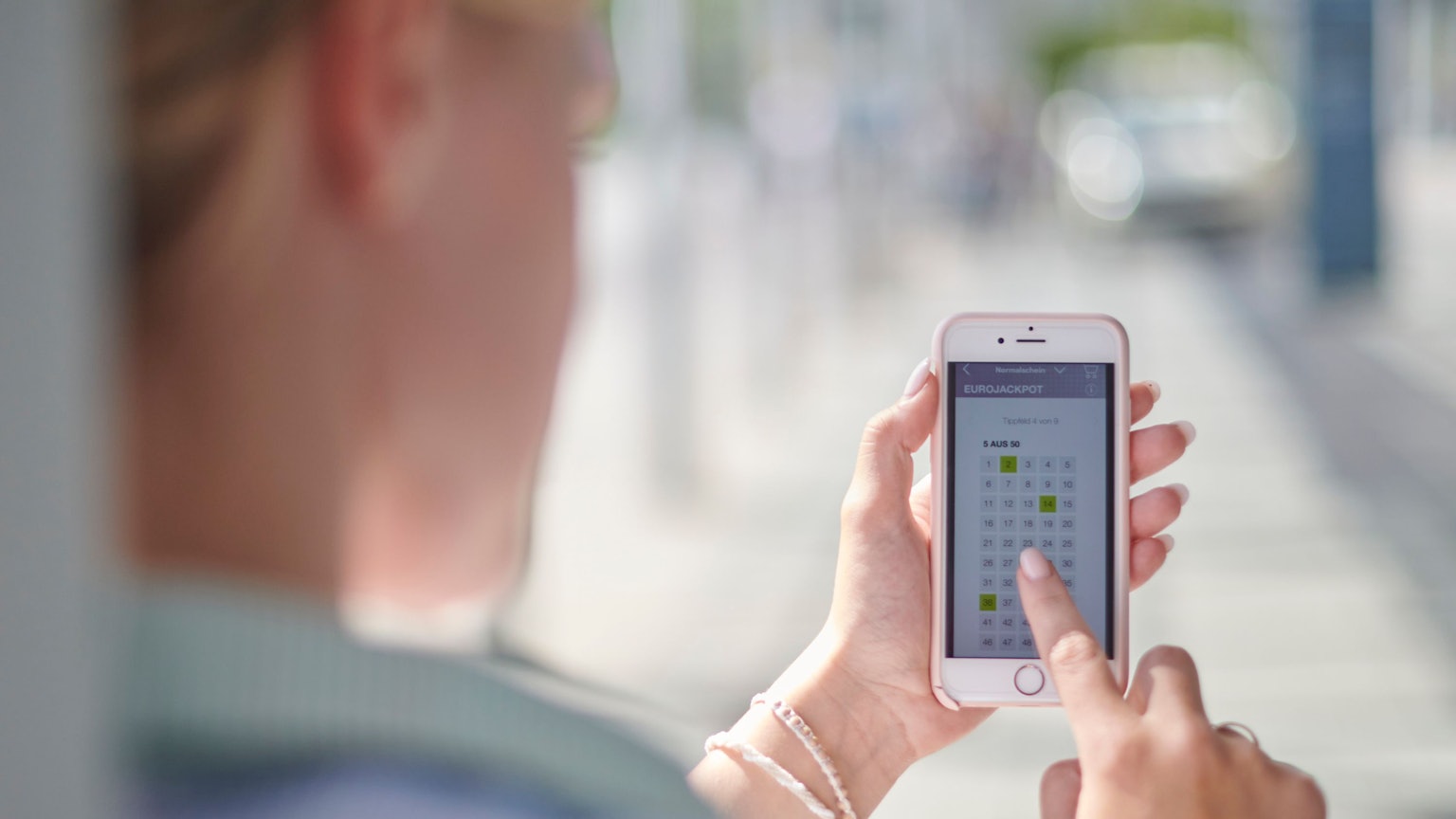 Frau tippt bei WestLotto auf dem Smartphone.