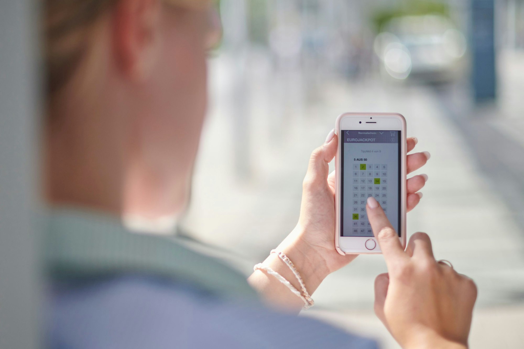 Frau tippt bei WestLotto auf dem Smartphone.