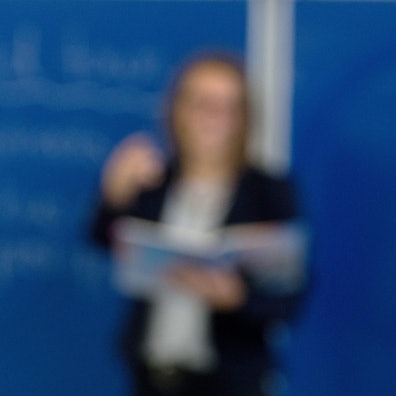 Das Bild zeigt einen Schüler, der sich meldet, dahinter eine Lehrerin an der Tafel. Der Lehrkräftemangel beschäftigt die Ständige Wissenschaftliche Kommission der Kultusministerkonferenz.