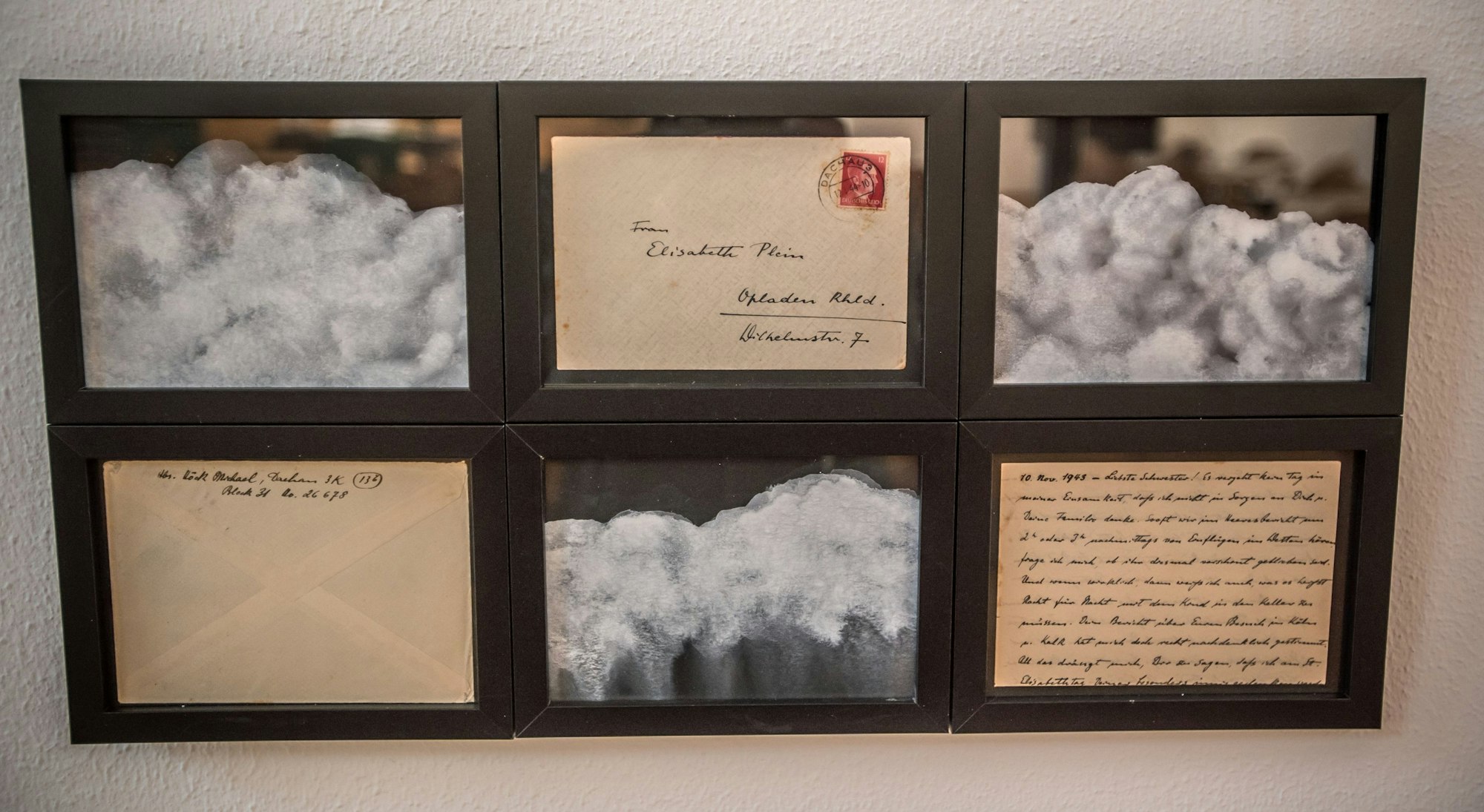 Ein Kunstwerk mit gerahmten Briefen und Wolkenbildern.